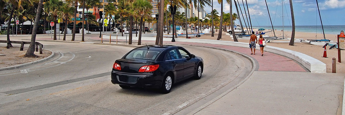 Photo of car driving along beach